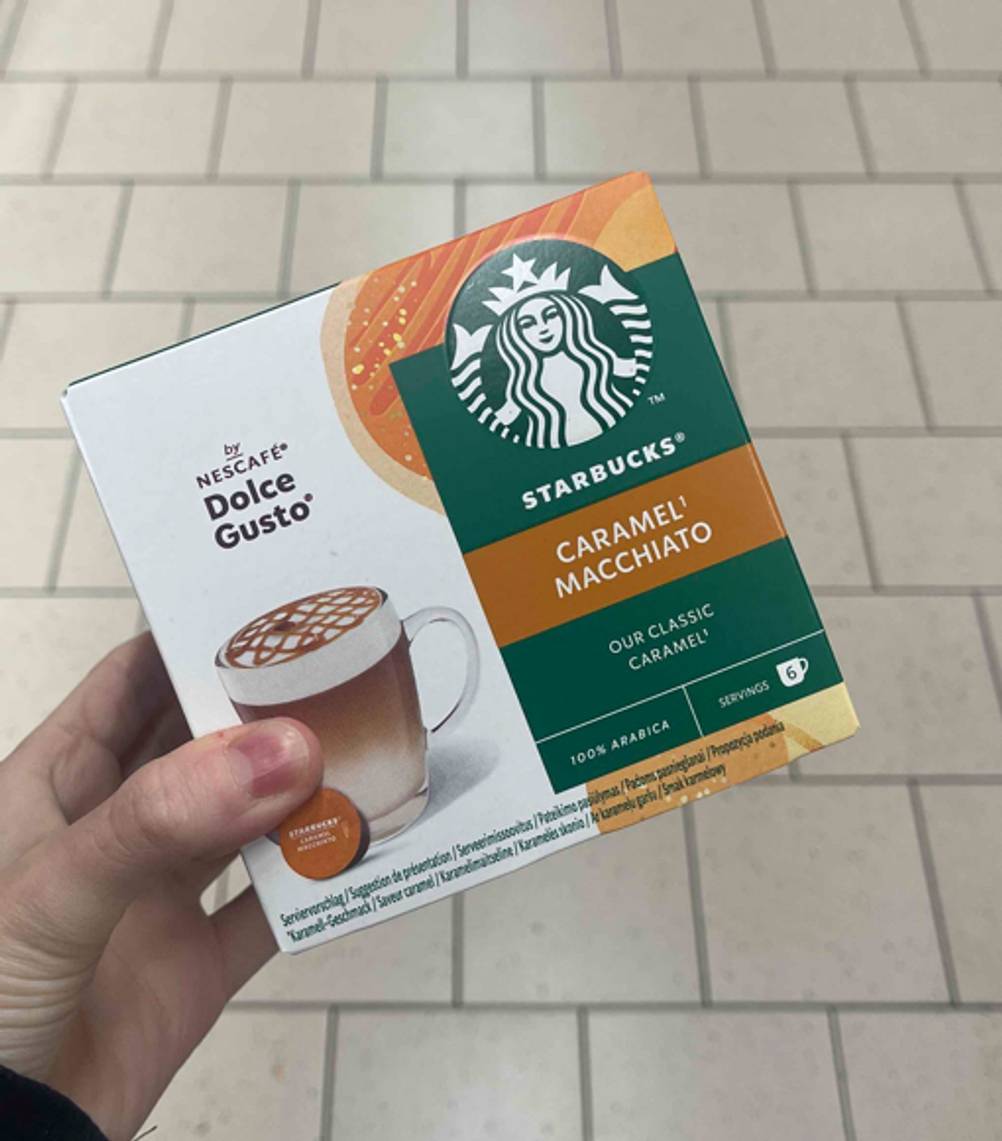 Der getestete Starbucks-Kaffee Caramel-Macchiato wird in der Hand gehalten.