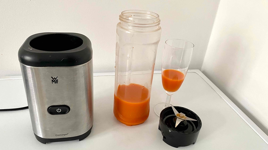 Getesteter Standmixer, Mixerflasche und Glas auf weißer Oberfläche stehend.