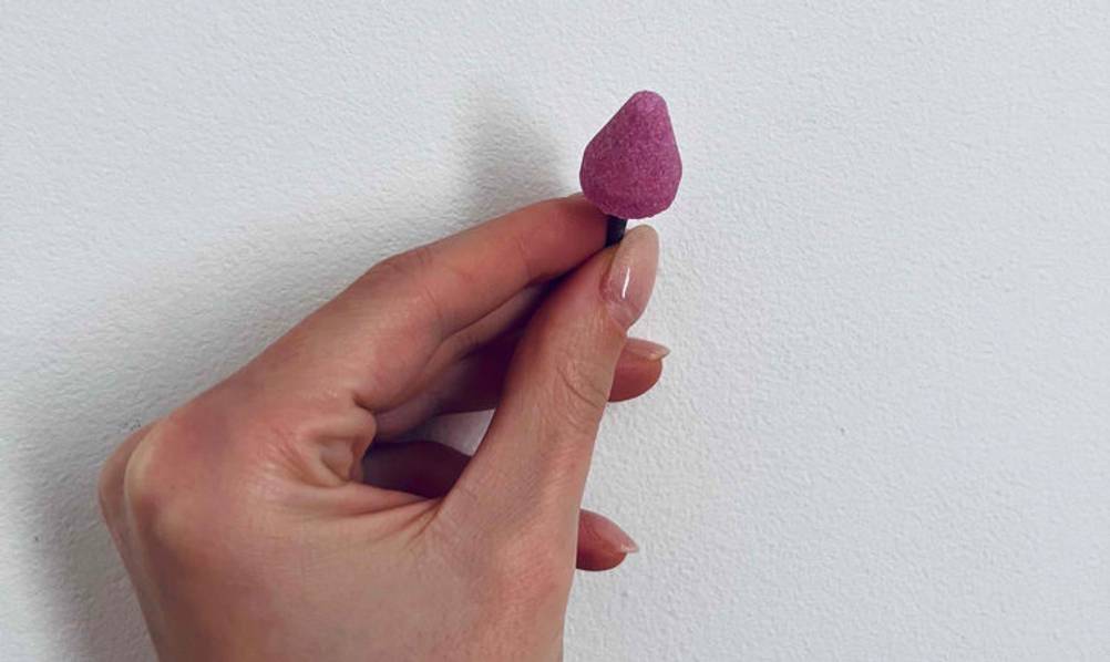 Diamantbohrkrone-Test: rosafarbige Diamantbohrkrone wird vor einer weißen Wand gehalten.