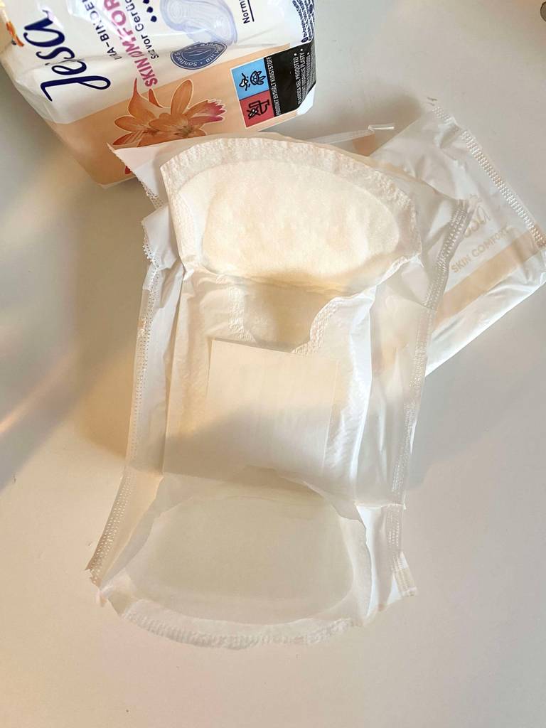 Eine ausgepackte Damenbinde im Test liegt ihrer weißen Kunststoffhülle.