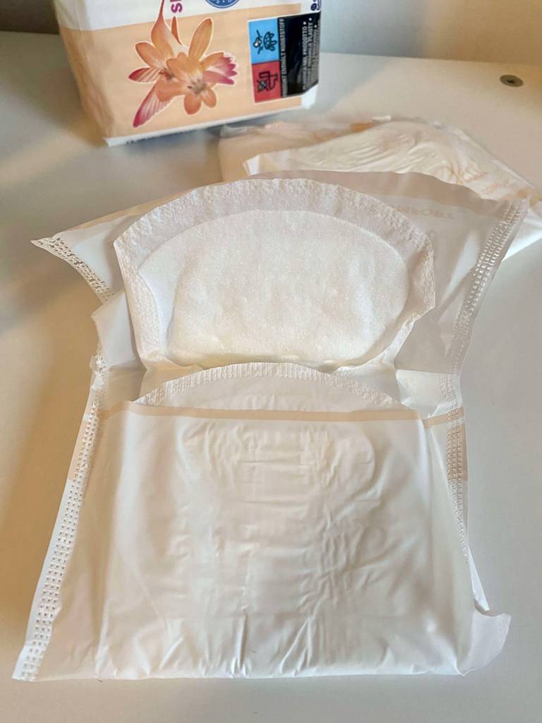 Eine halb geöffnete Damenbinde im Test liegt auf einer weißen Oberfläche.