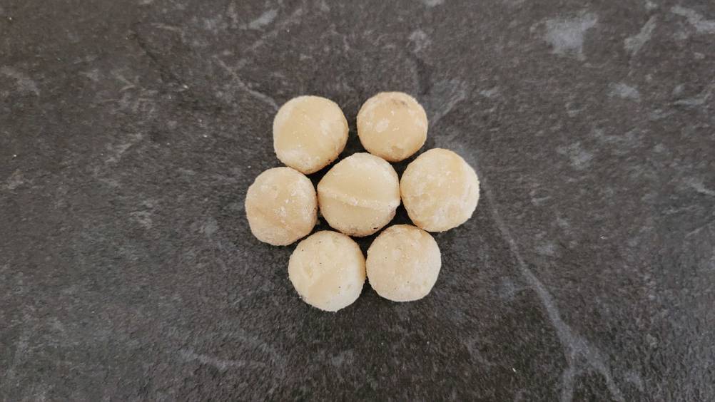 Macadamia-Nüsse getestet: Einige Nüsse liegen trapiert auf einer dunklen Oberfläche