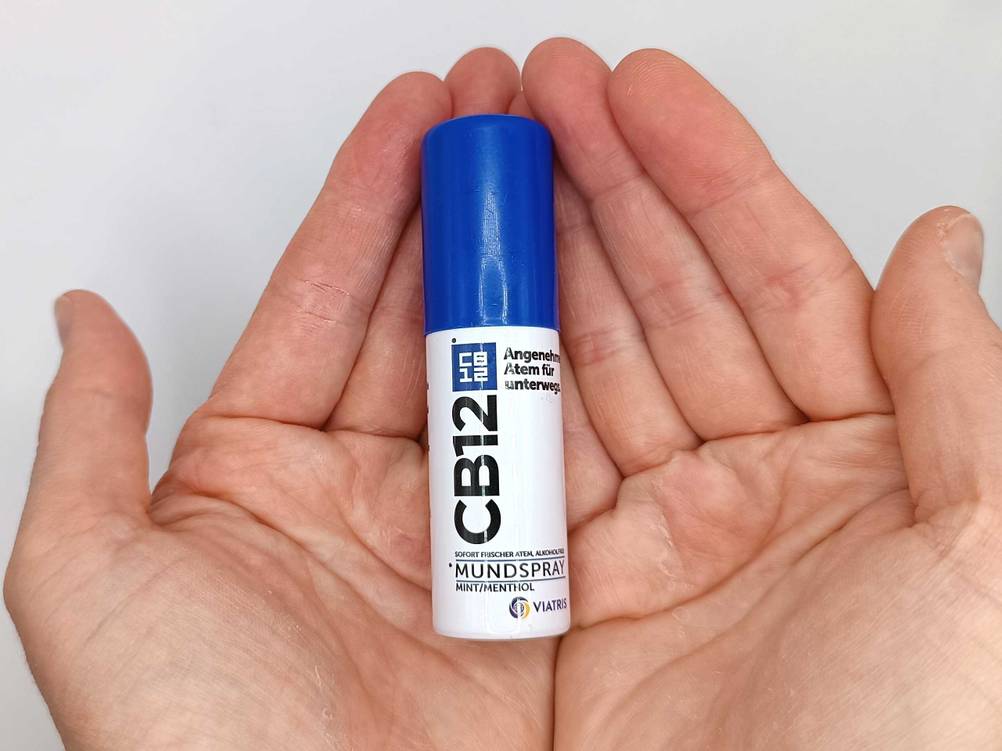 Mundspray in der Hand.
