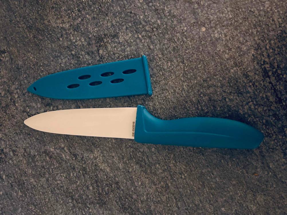 Keramikmesser im Test: Keramikmesser mit blauem Griff liegt neben Schutzkappe.