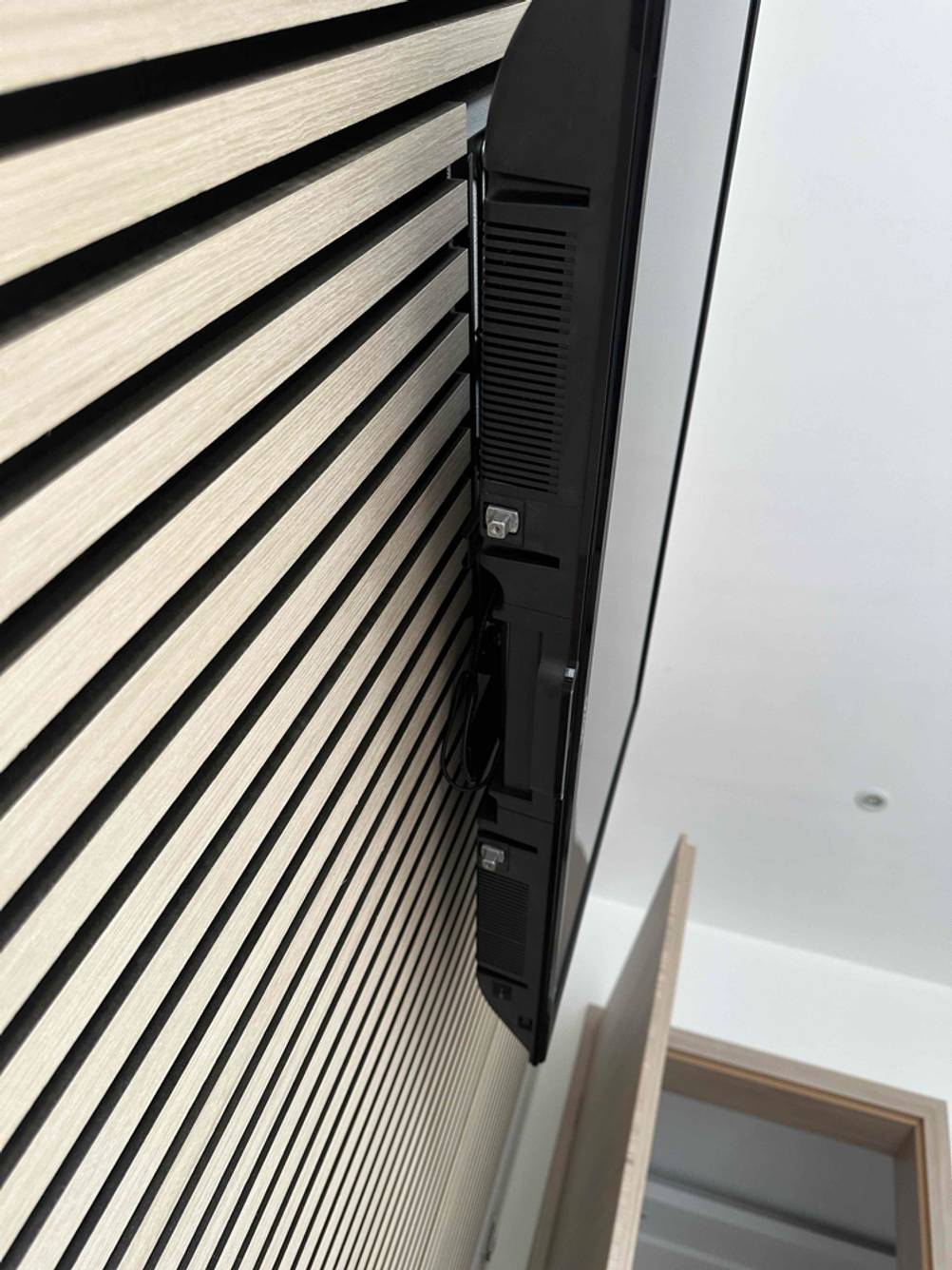 Seitenansicht eines getesteten Dyon-Fernsehers, welcher auf einer Wand hängt.
