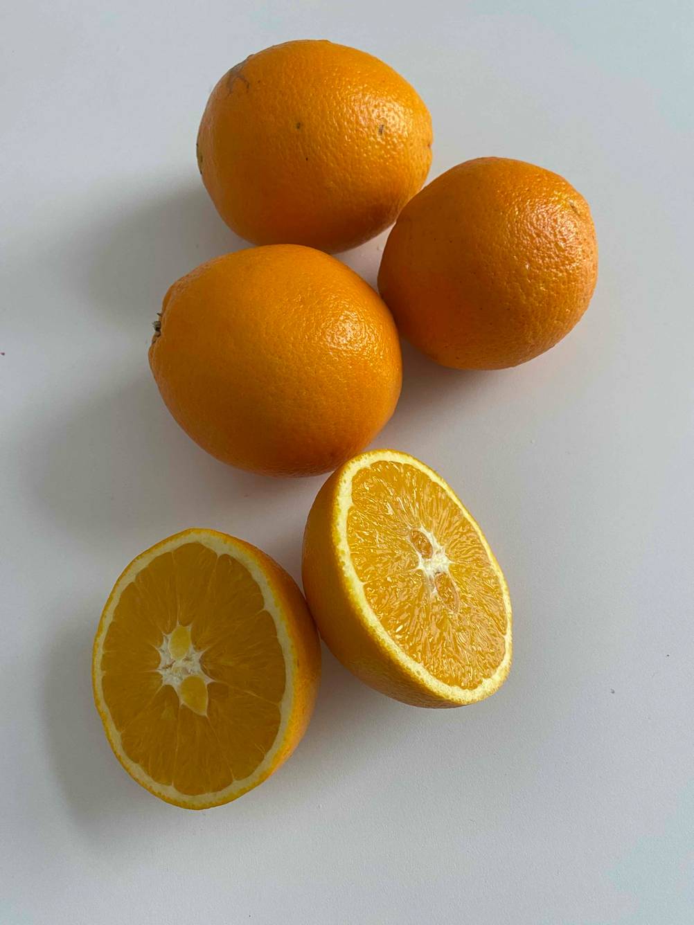 Eine aufgeschnittene Saftorange, die getestet wurde, liegt neben ganzen Orangen.
