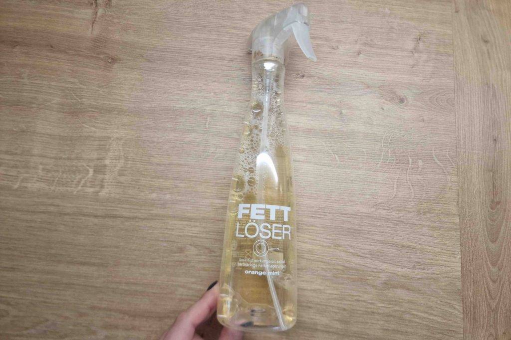 Im Test: Eine Flasche Fettlöser liegt auf einer Holzoberfläche.