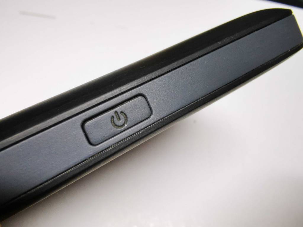 Der Huawei-Router im Test steht auf einer weißen Oberfläche, im Fokus die Einschalttaste.