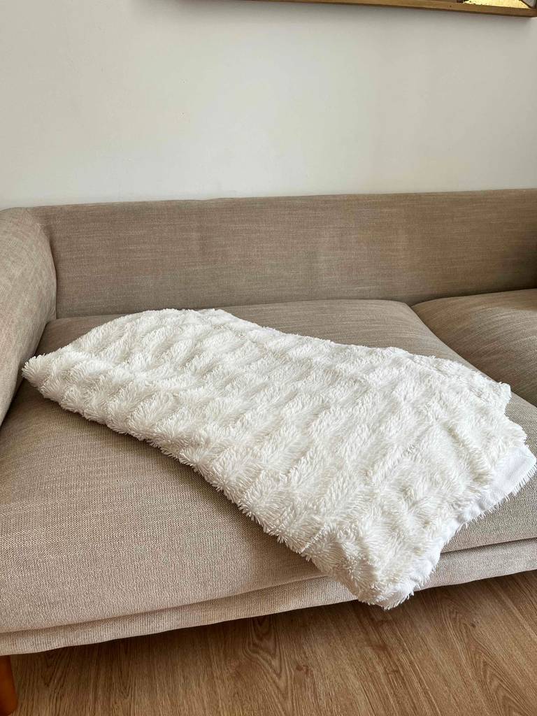Kuscheldecke im Test: Eine Decke liegt über den Polstern einer beigen Couch