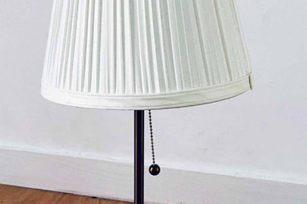 Schreibtischlampe im Test: Lampe mit weißem Lampenschirm auf einem Holzboden stehend.