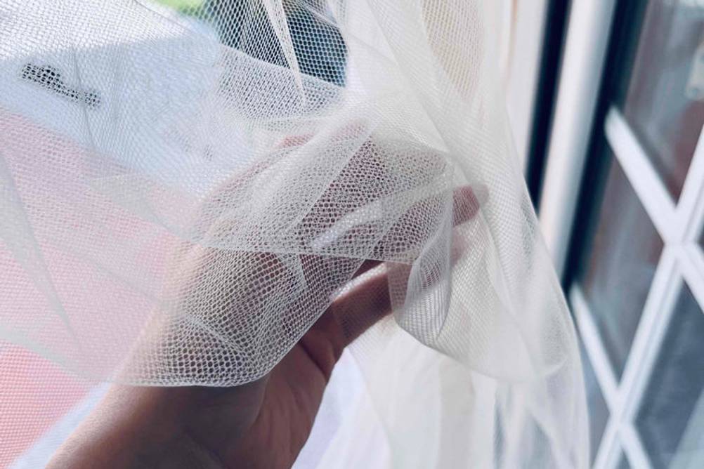 Im Test: Eine Hand hält einen Insektenschutz-Vorhang vor eine Tür.