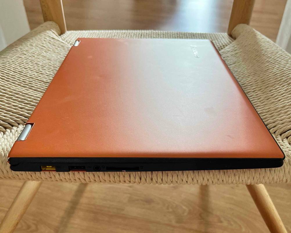 Lenovo-Yoga-Test: ein Laptop mit orangefarbenem Gehäuse liegt auf einem Sessel.