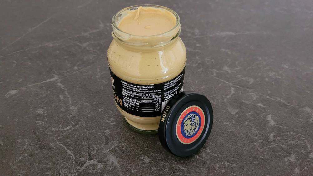 Dijon Senf im Test: Ein Glas Senf, der Deckel lehnt am Glas auf einer dunklen Oberfläche