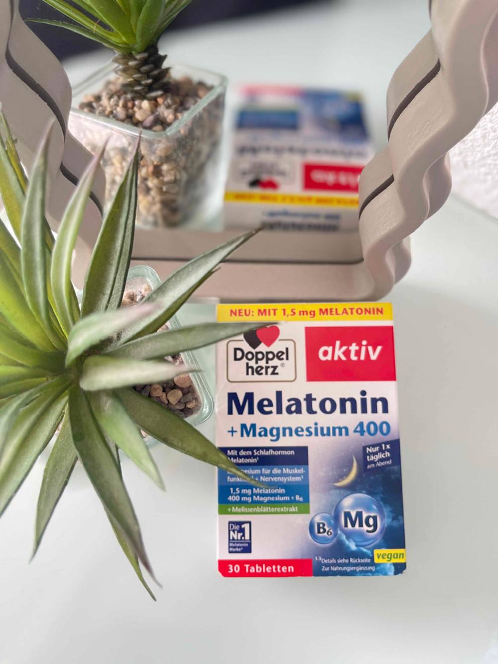 Die Verpackung der getesteten Melatonin-Tabletten liegt neben einer Pflanze.