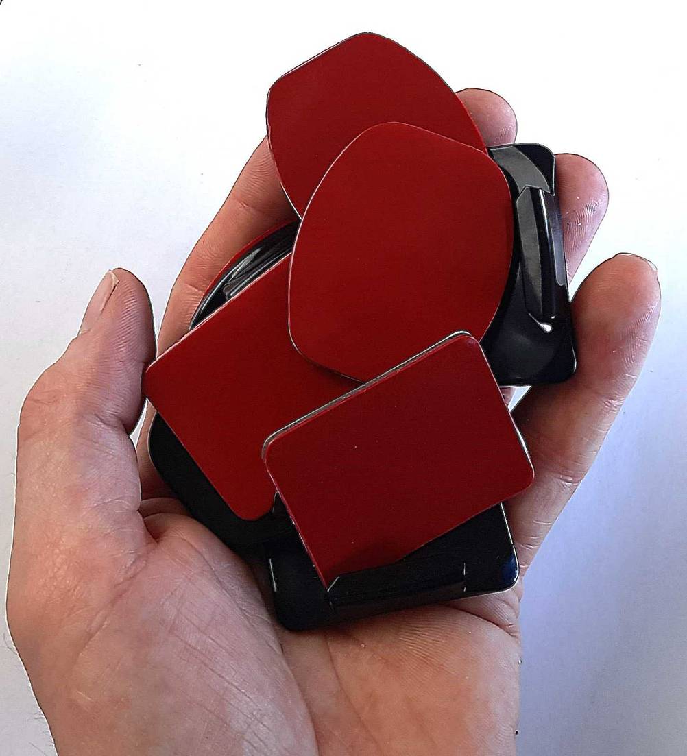 Die GoPro-Klebehalterungen werden in der Hand gehalten.
