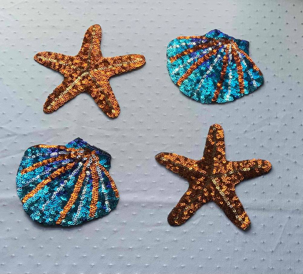 Im Test: Auf einer hellen Oberfläche liegen mehrere Patches, hier in Form von Seesternen und Muscheln.