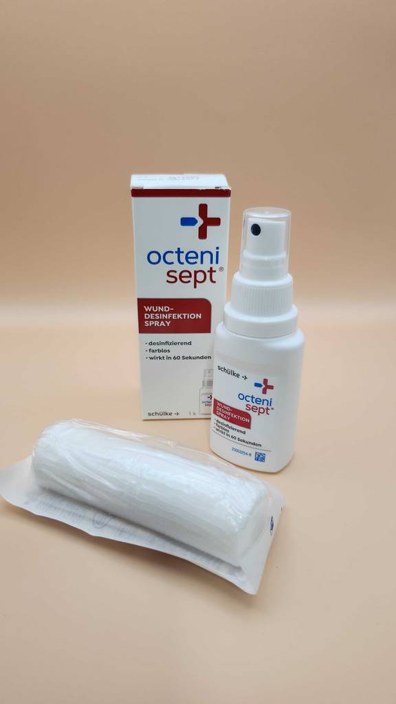 Das getestete Wunddesinfektionsmittel steht auf einem Tisch mit einem Verband und der Verpackung.
