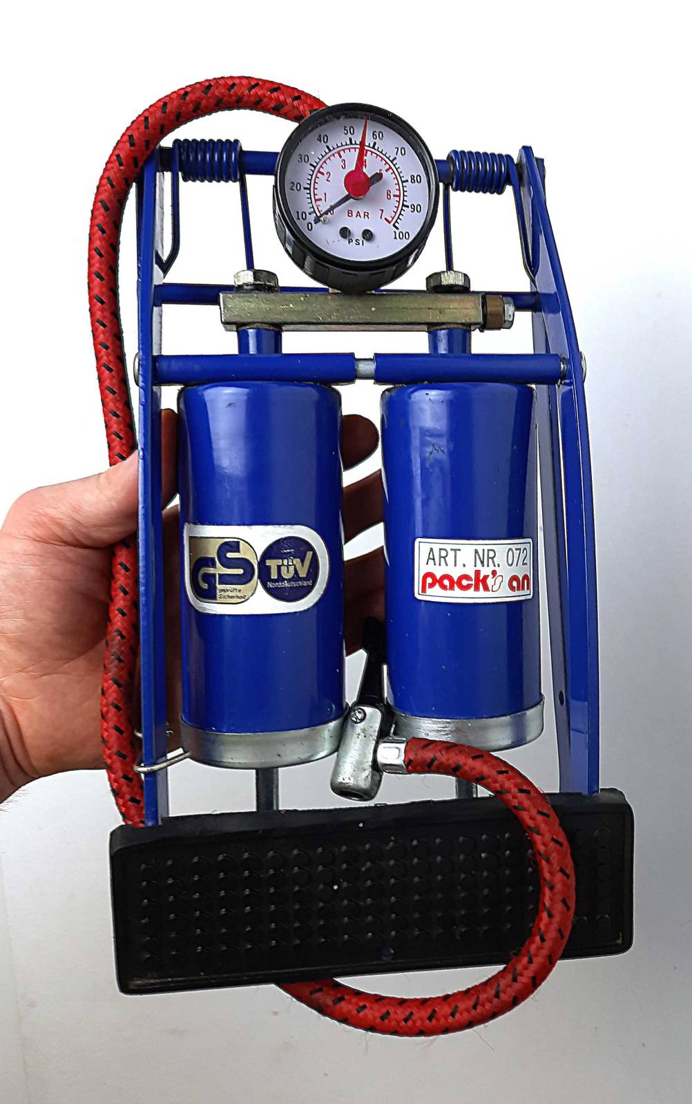 Die gesamte Fußluftpumpe, welche getestet wurde wird in der Hand vor einer weißen Wand gehalten.