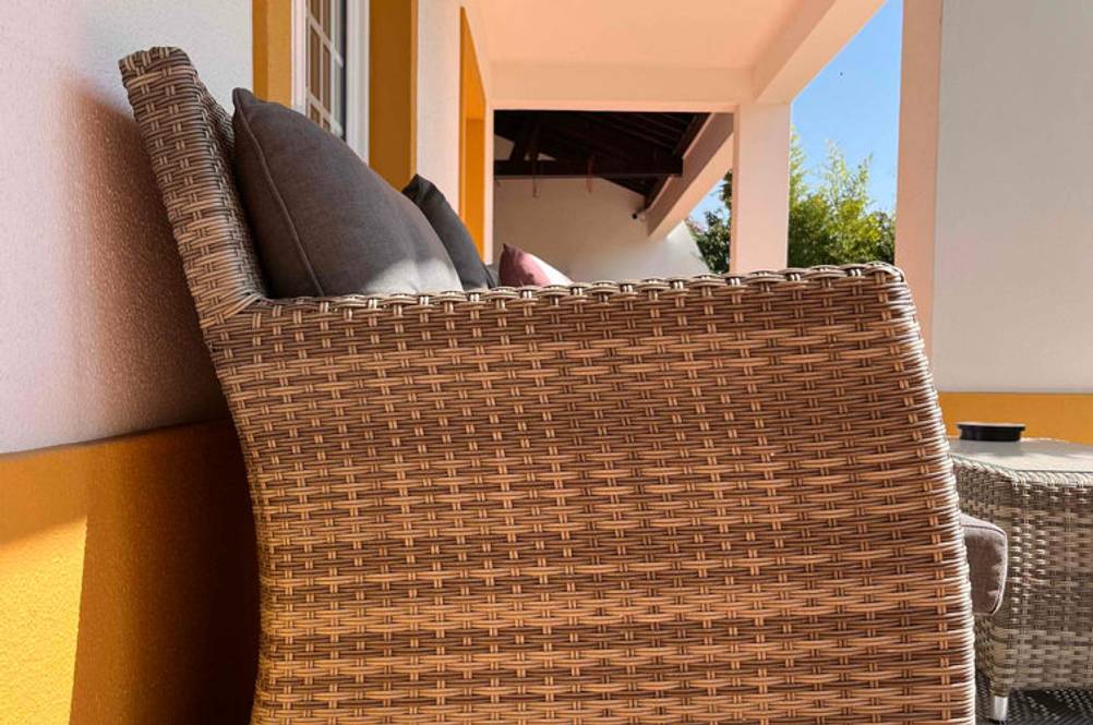 Rattansofa getestet: Rattansofa steht auf überdachten einer Terasse - Fokus auf den seitlichen Teil des Modells.