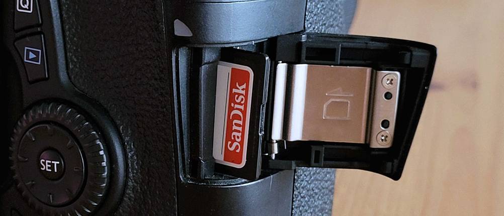 Speicherkarte-Test: Eine Speicherkarte von SanDisk steckt in einer Kamera. Die Sicherungsklappe ist geöffnet.