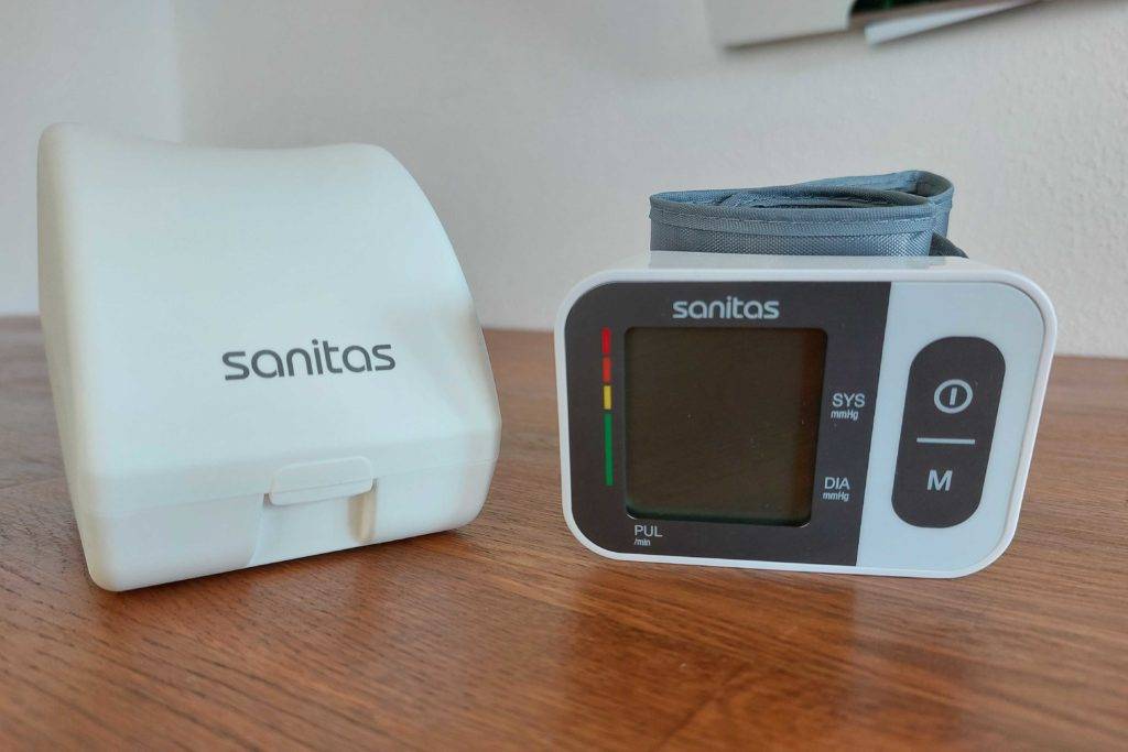 Sanitas-Blutdruckmessgerät getestet: Das Messgerät liegt neben seiner Schutzverpackung auf einer Holzoberfläche