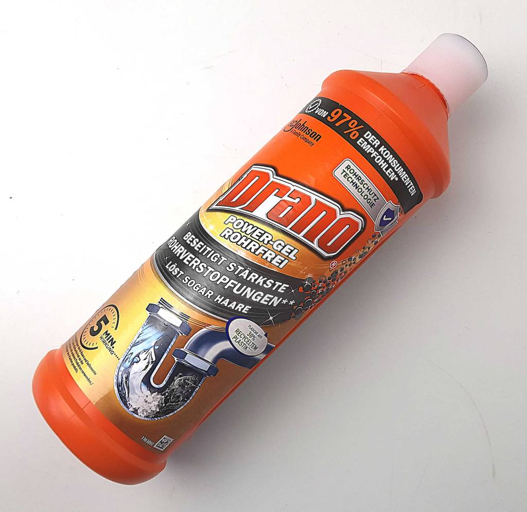 Rohrreinigung im Test: Der Drano-Rohrreiniger liegt in der orangefarbenen Kunststoffflasche auf einer weißen Oberfläche.