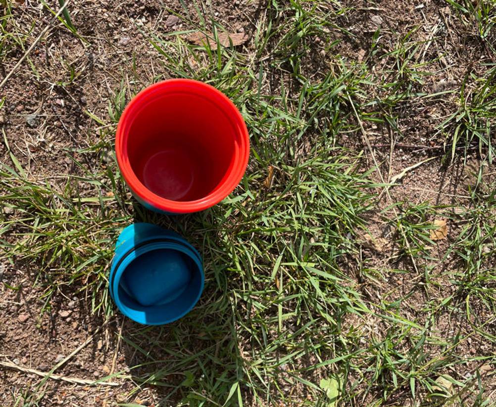 Coffee-to-go-Becher-Test: Ein offener To-go-Becher steht in der Wiese. Daneben liegt der Deckel. 