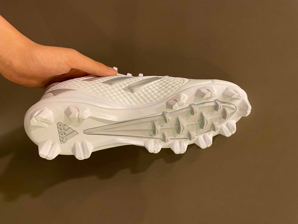 Fußballschuhe-Damen im Test: weißer Fußballschuh für Damen wird mit der Sohle ersichtlich in der Hand gehalten.
