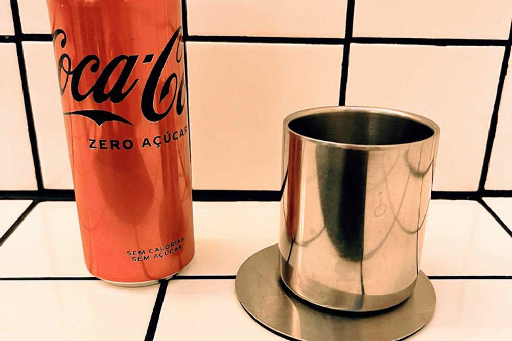 Im Test: Ein Edelstahlbecher steht neben einer Cola Dose auf einer Fließenoberfläche