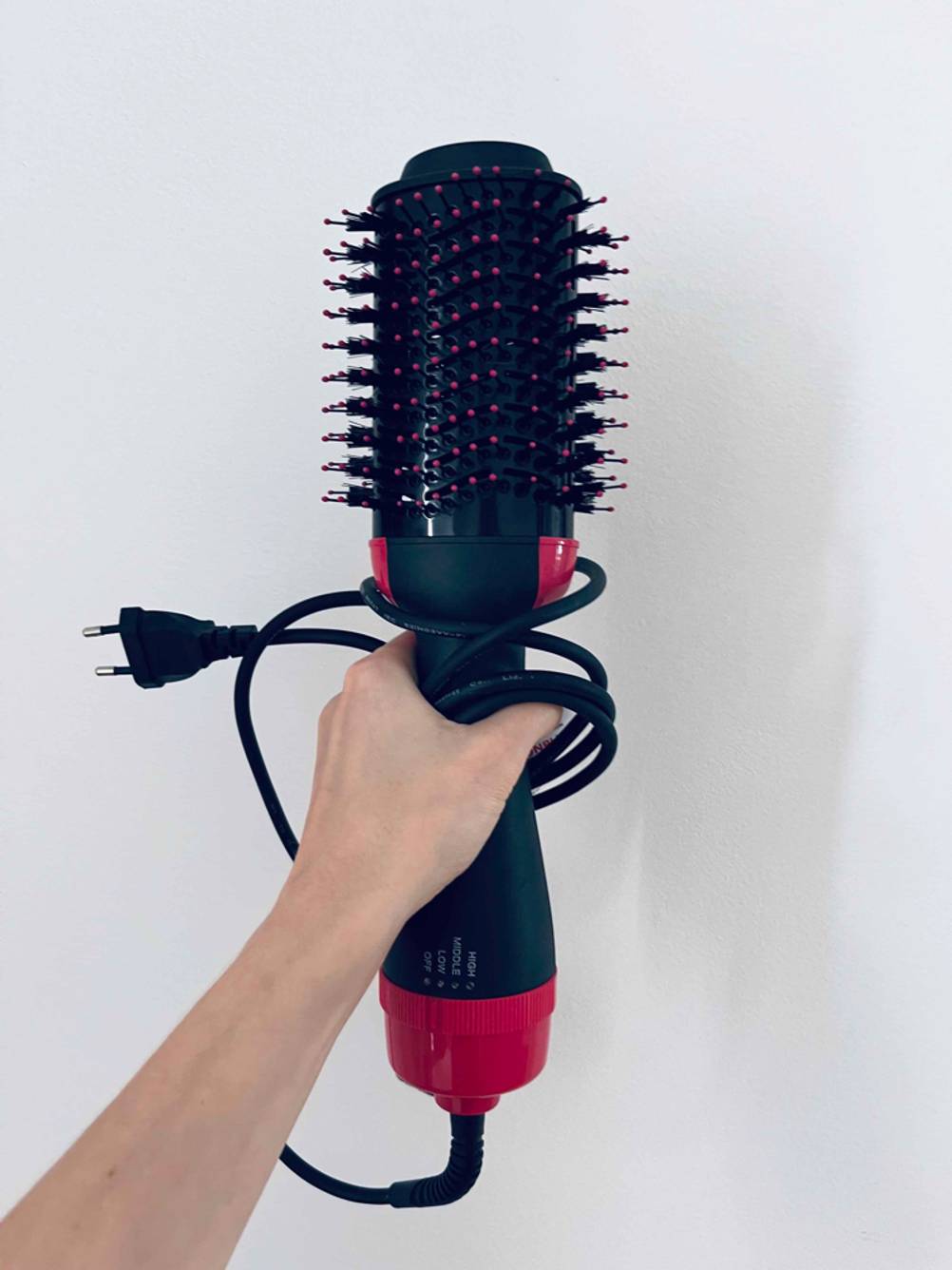 Glättbürste-Test: eine Glättbürste wird mit dem Kabel vor einer weißen Wand gehalten.
