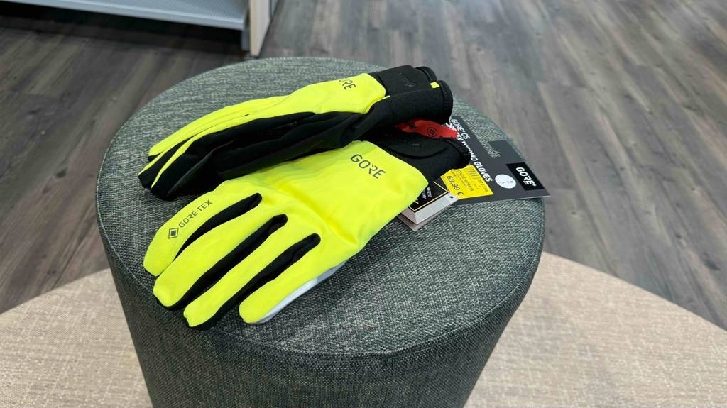 Ein Paar getestete Fahrradhandschuhe für den Winter liegen auf einem grauen Hocker übereinander.