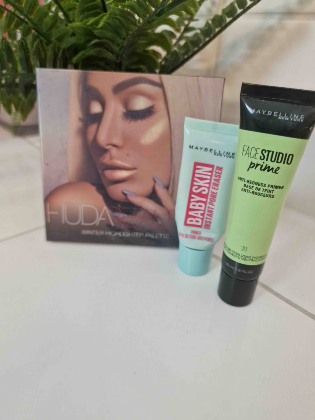 Zwei Make-up-Primer mit Lidschattenpalette im Hintergrund.