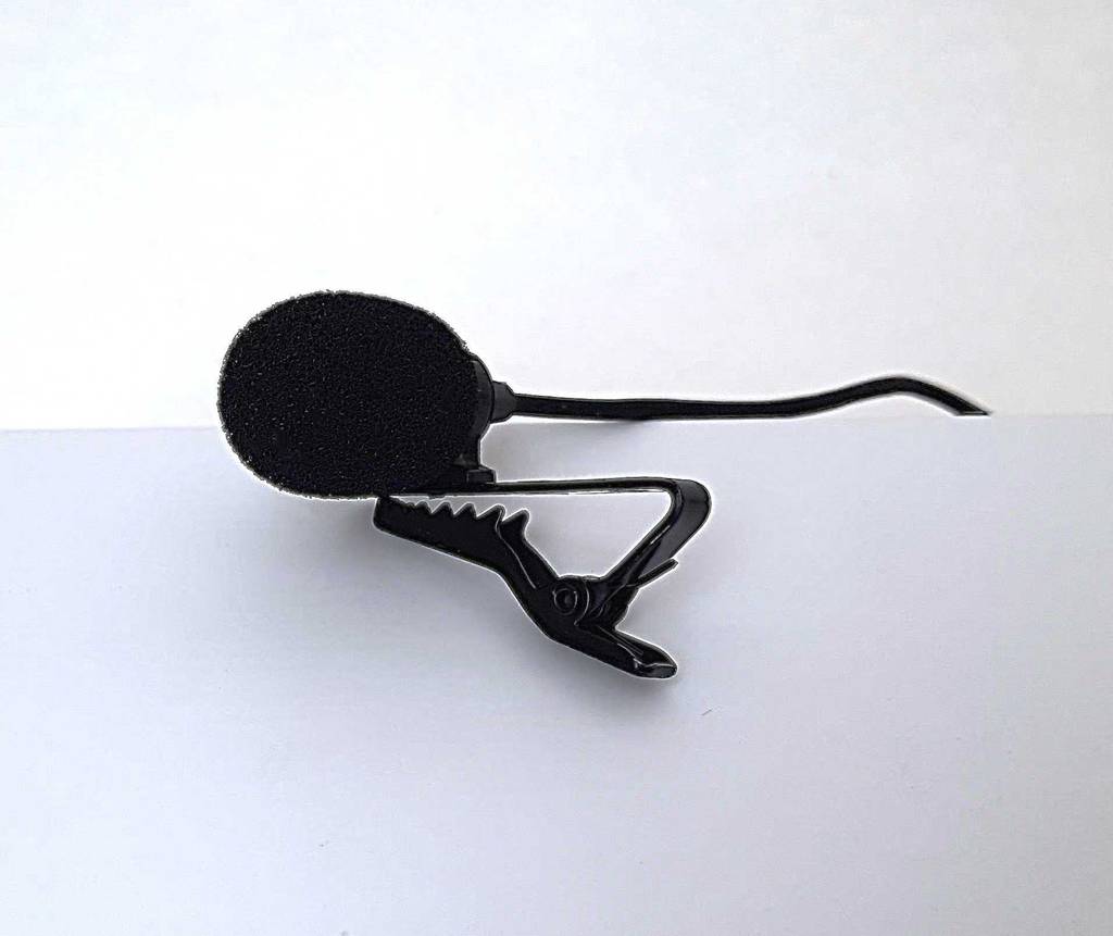 Ansteckmikrofone im Test: Das schwarze Mikrofon liegt inklusive Anstecker auf einer weißen Oberfläche.