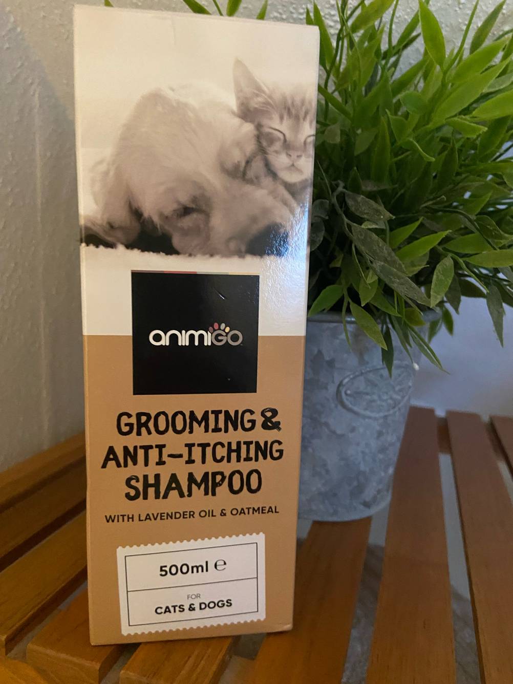 Die Verpackung eines getesteten Milben-Shampoos für den Hund steht vor einer Pflanze.