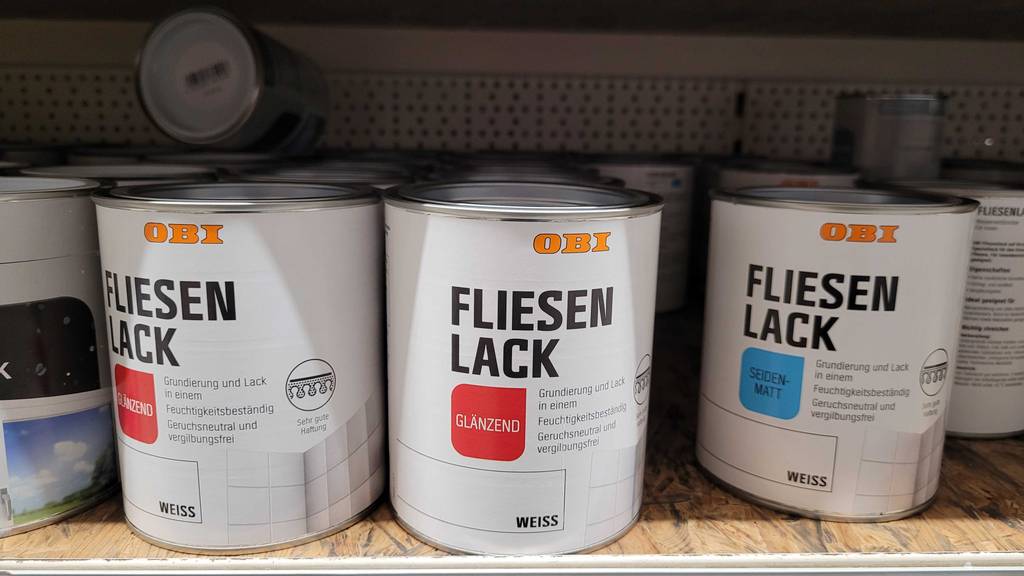 Test: mehrere Dosen des Fliesenlacks stehen in einem Regal in glänzender und seiten-matter Variante.