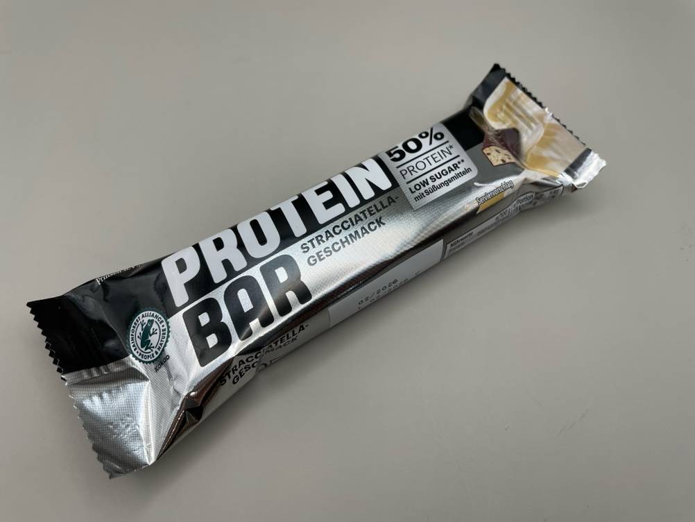 Der Weider-Proteinriegel, welcher getestet wurde ist auf einer grauen Fläche platziert.