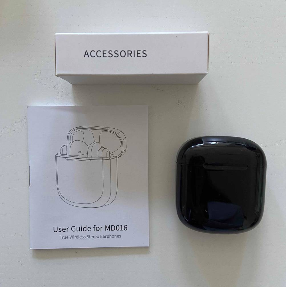 In-Ear-Kopfhörer im Test: schwarzes Case liegt neben der Gebrauchsanweisung und Verpackung.