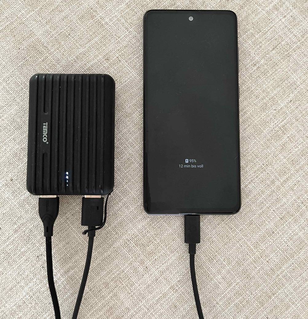 Powerbank-powerbank-10000mah im Test: Eine Powerbank mit angeschlossenem Handy daneben liegend.