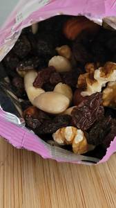 Ein Bild einer geöffneten Packung Studentenfutter, die verschiedene Arten von Nüssen und Trockenfrüchten wie Mandeln, Cashewnüsse, Rosinen und andere enthält.