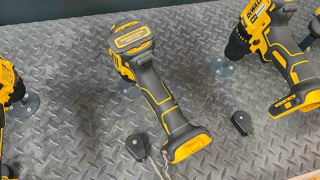 Ansicht von oben auf mehrere gelb-schwarze DeWalt-Akku-Bohrschrauber im Test, die auf einem grauen Metallregal im Verkaufsbereich ausgestellt sind.