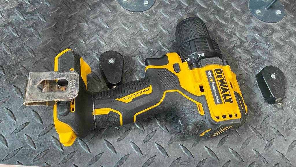 Ein gelb-schwarzer, gesicherter DeWalt-Akku-Bohrschrauber im Test liegt seitlich auf einem grauen Metallregal im Verkaufsbereich.