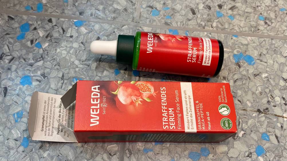 Eine Flasche getestetes Gesichtsserum horizontal neben seiner Originalverpackung.