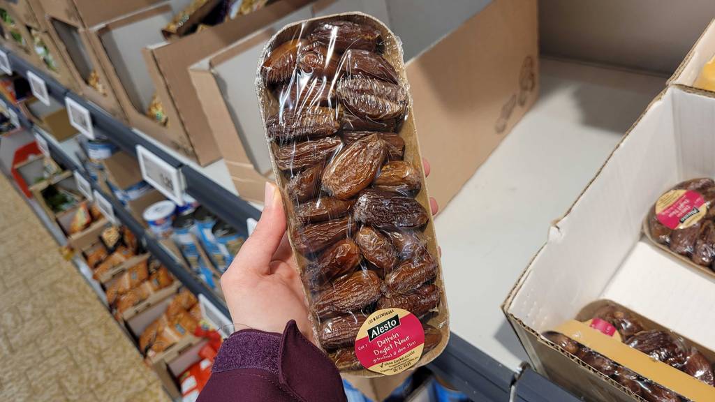 Eine Packung der getesteten getrocknete Datteln werden in der Hand gehalten.
