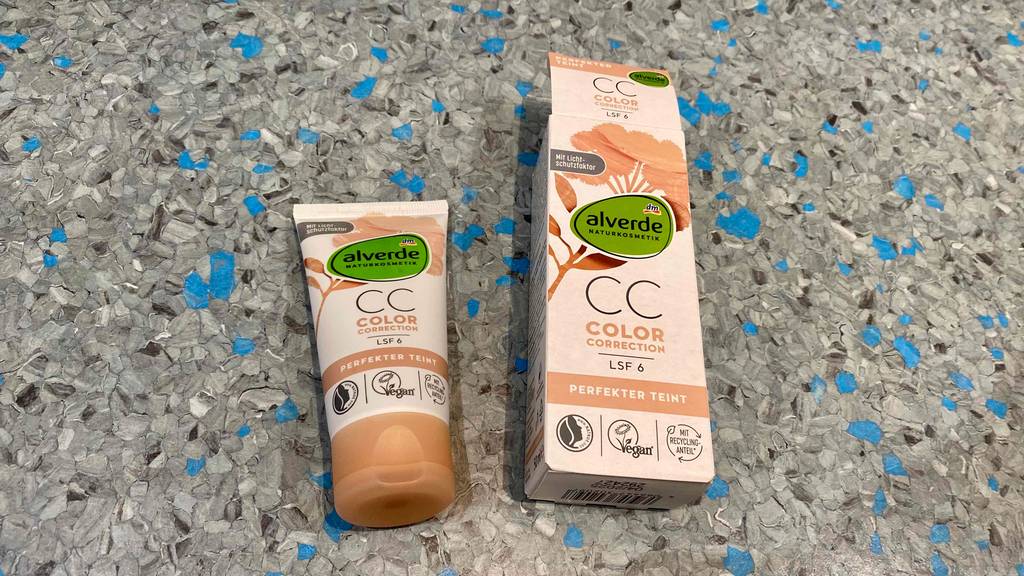 getönte Tagescreme im Test: Eine Tube Creme neben Verpackung auf einer bunten Oberfläche
