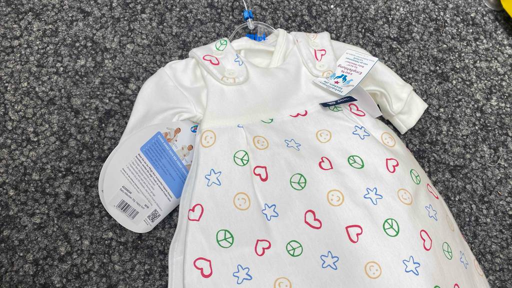 Ein getesteter Baby-Winterschlafsack liegt auf einem grauen Teppich.