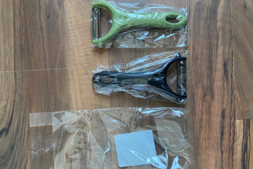 Pendelschäler im Test: Zwei in Folie verpackte Schäler nebeneinander auf einer Holzoberfläche.