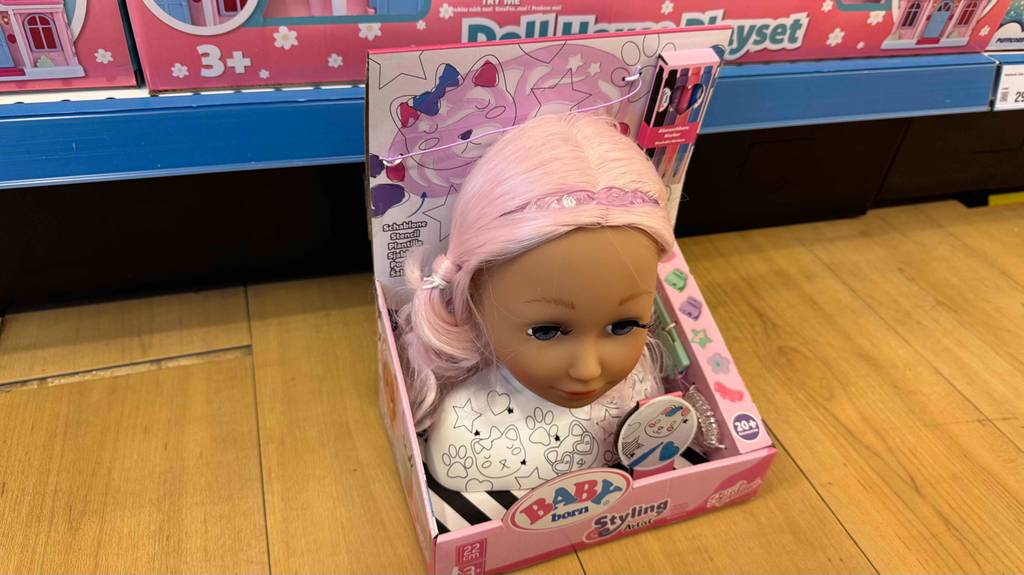 Ein Frisierkopf der getestet wurde mit rosa Haaren und einem Haarreifen darauf.