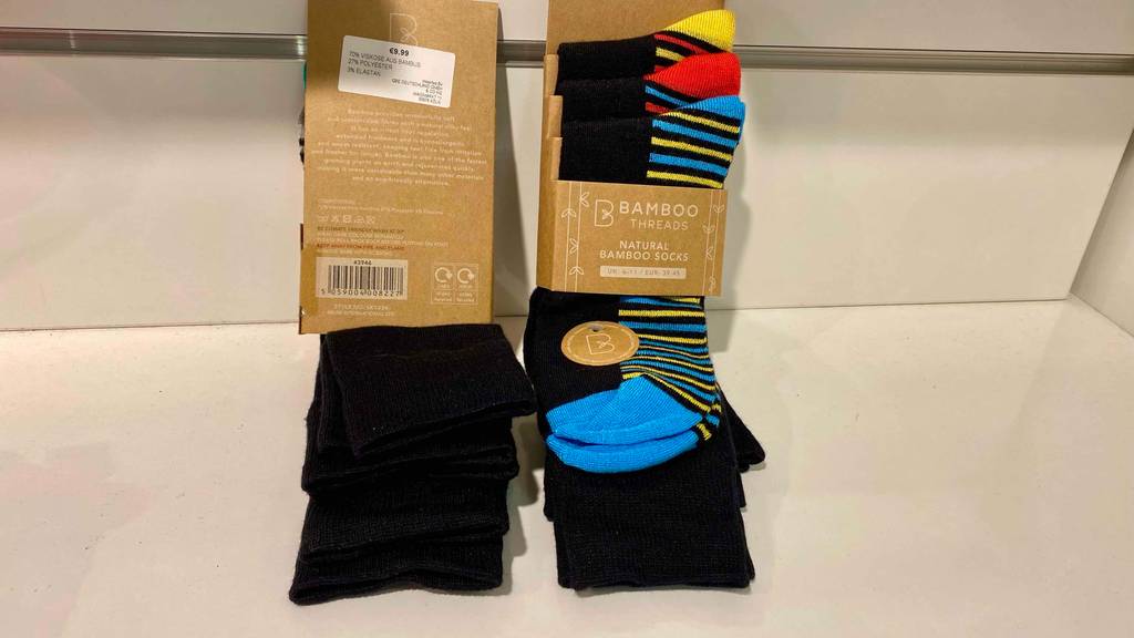 Im Test: Eine Packung Bambussocken von hinten, eine Packung von vorne lehnen an einer hellen Wand.