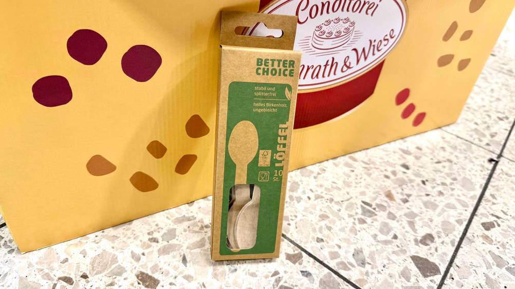 Die getesteten Holzlöffel stehen vor einem Aufsteller in der Verpackung.