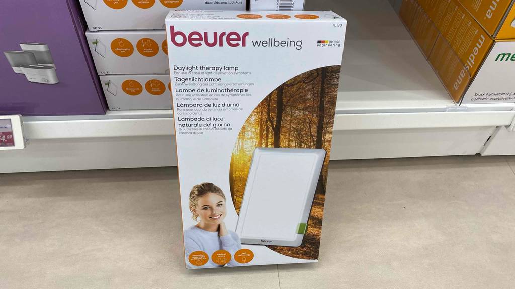 Im Test: Eine verpackte Beurer-Tageslichtlampe lehnt an einem Regalbrett.